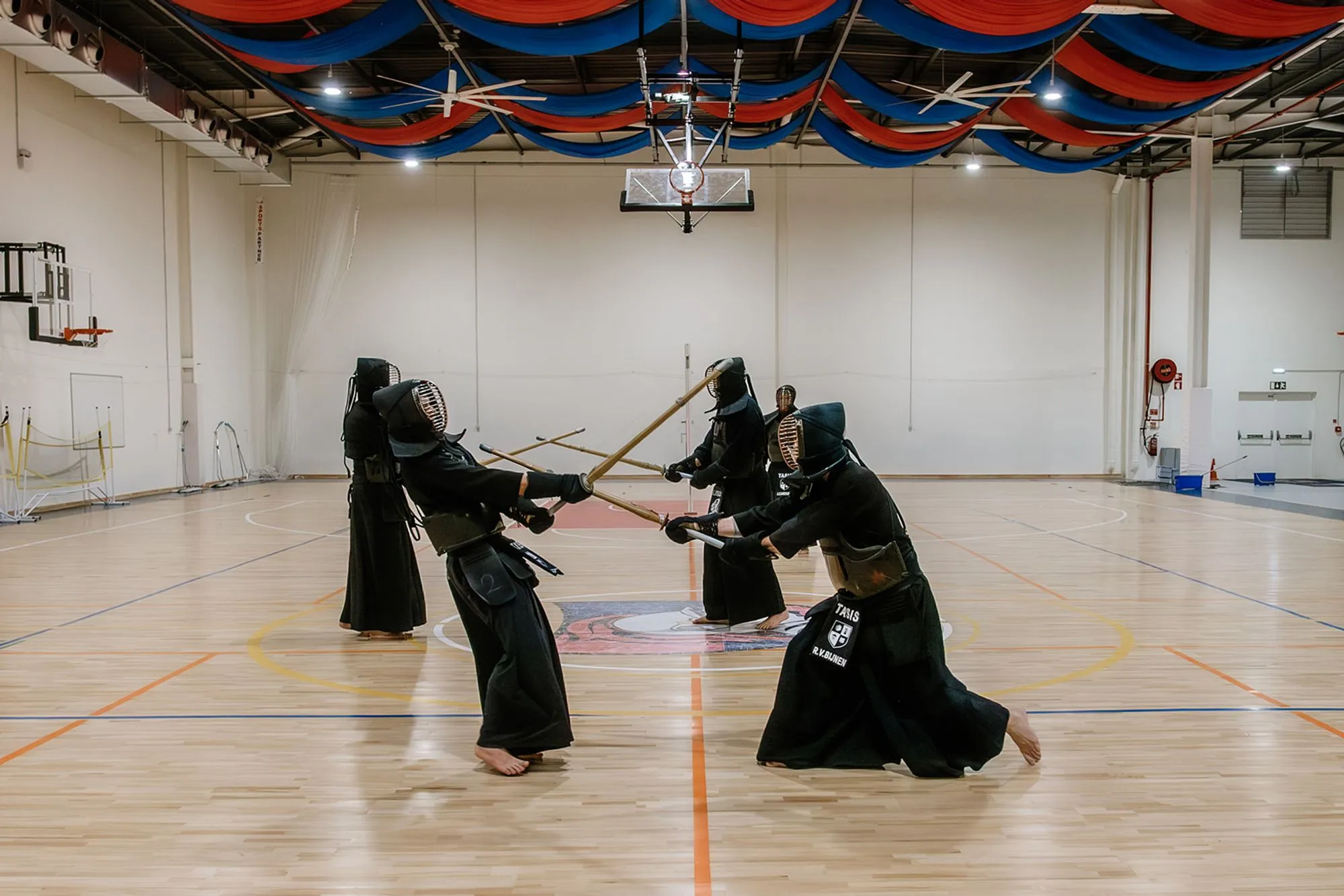 Four kendoka sparring, one dropping into a low stance